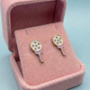 Earrings resembling tennis rackets in a pink jewelry box on a light blue background