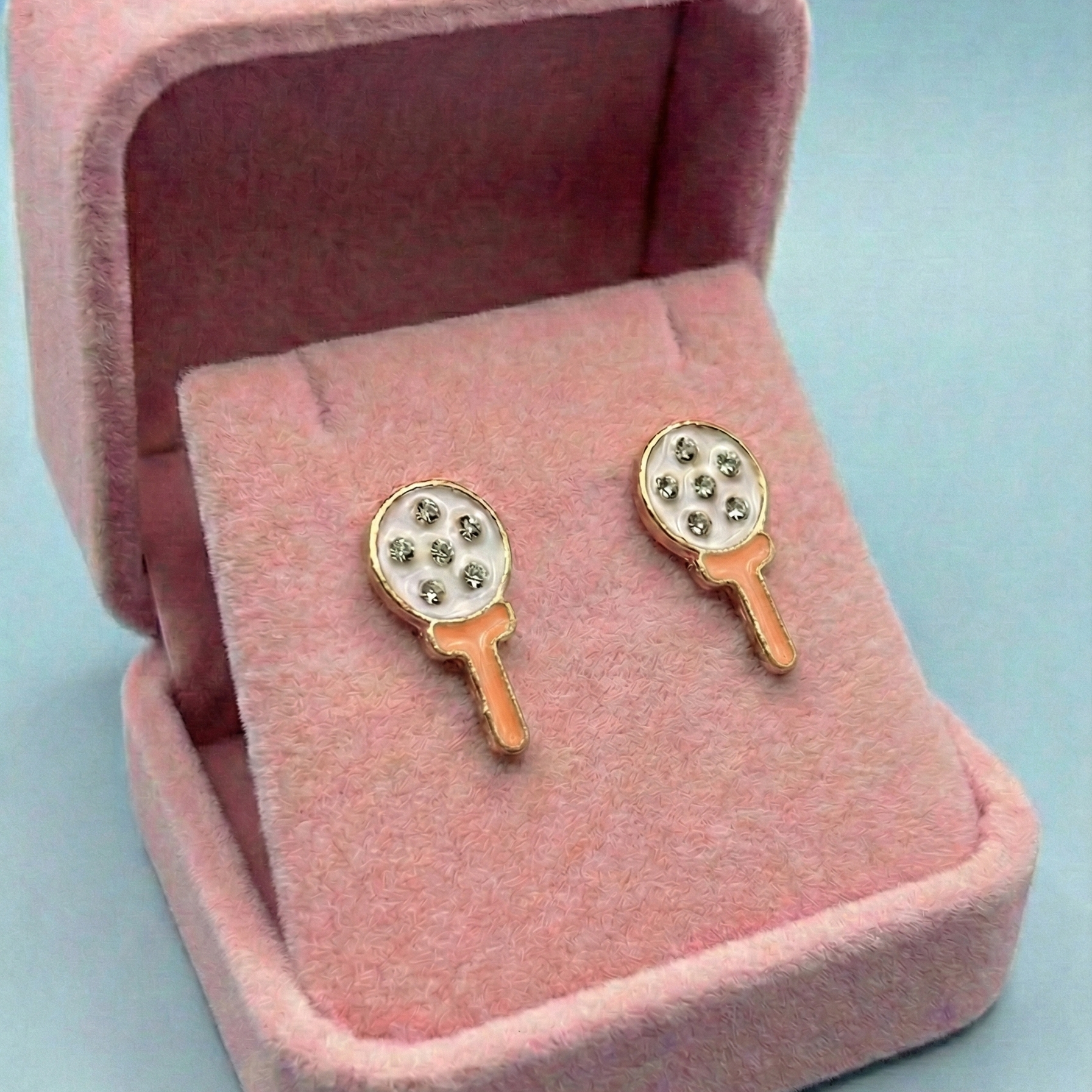Pair of earrings in a pink jewelry box on a light blue background