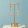 Gold earring stand with golf-themed earrings on a light blue background
