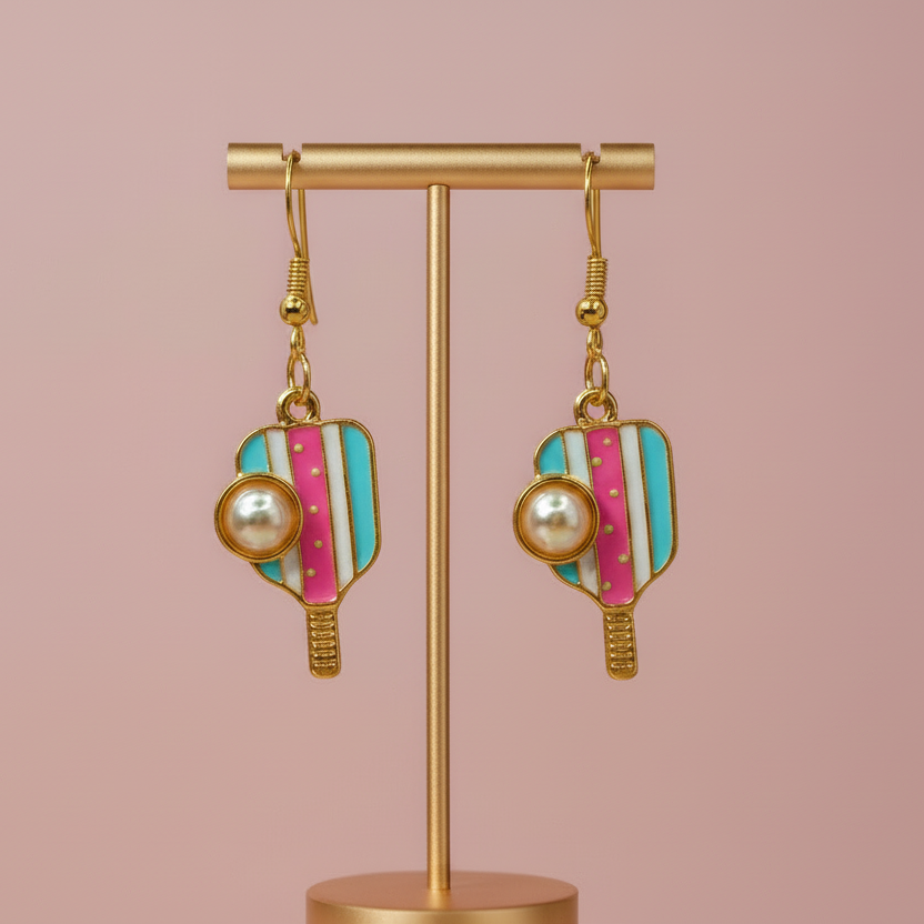 Gold earrings with colorful striped design on a stand against a pink background