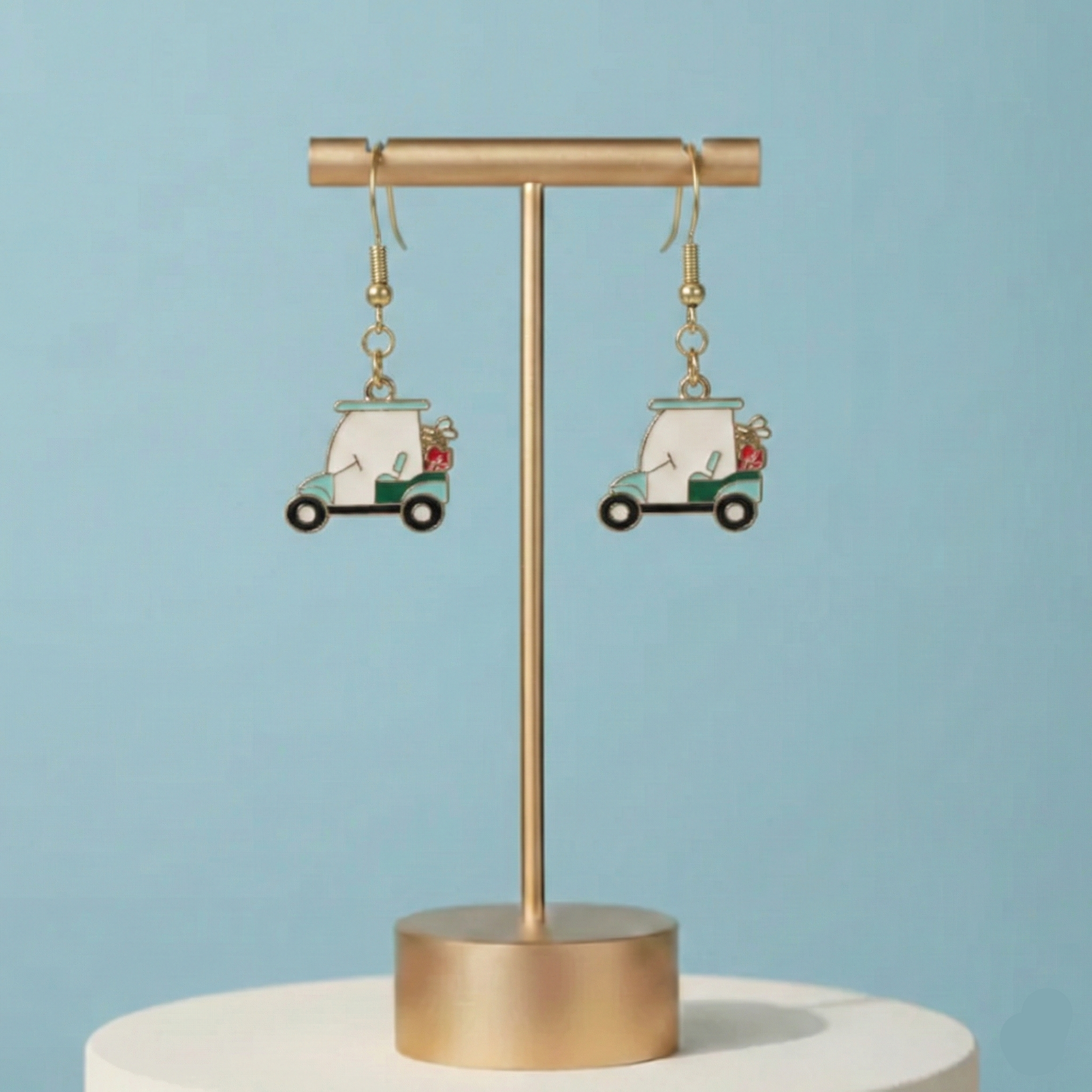 Earrings with car design on a gold stand against a light blue background