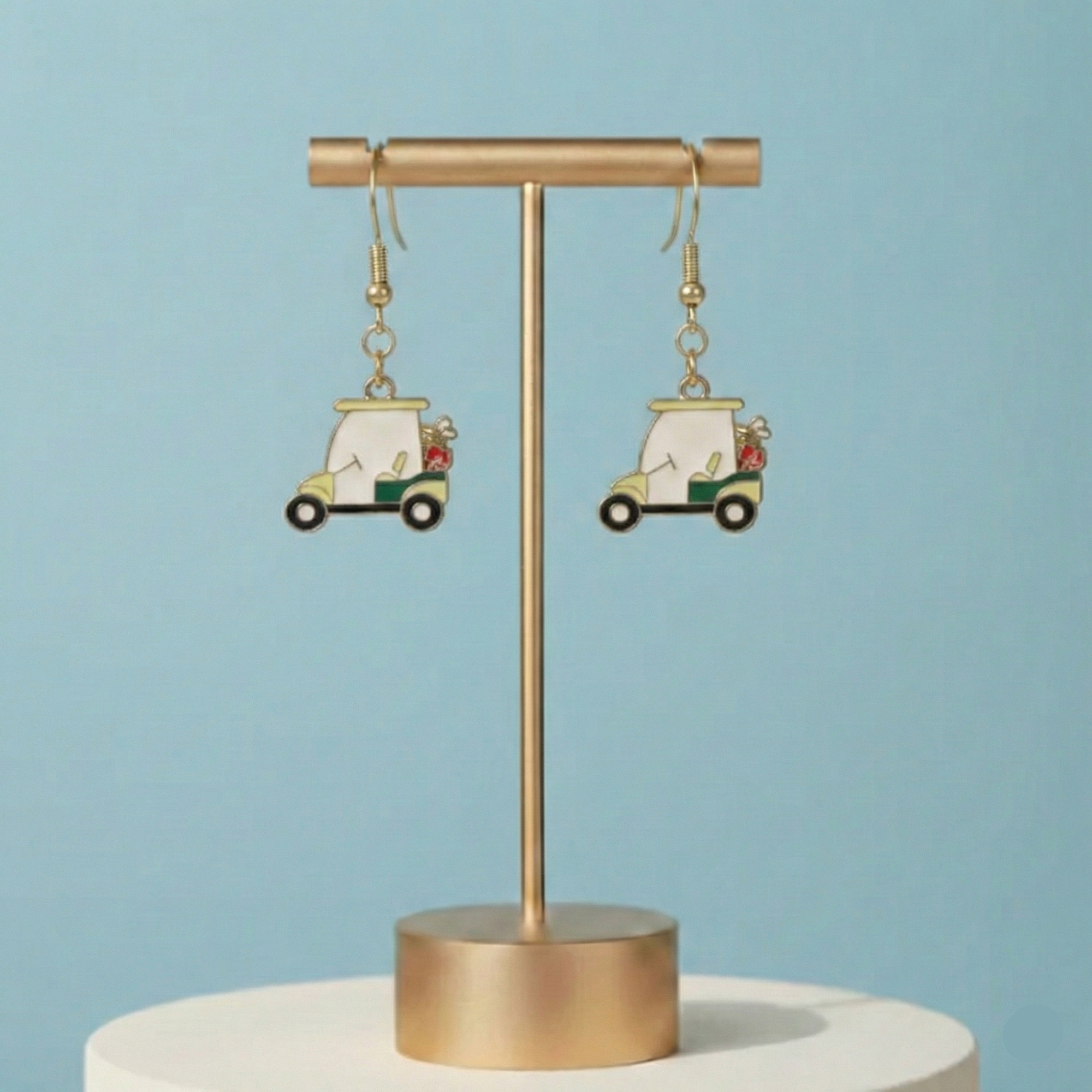 Pair of earrings on a gold stand against a light blue background